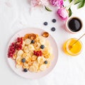 Tiny pancakes with berries, honey, flowers, coffee. Pancake cereal. The concept of Breakfast, food trends. Copy space