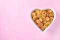 Tiny pancakes for breakfast in white bowl-shaped heart on pink background, Top view, Copy space for text or design Royalty Free Stock Photo