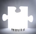 Tiny people and a jigsaw puzzle piece Royalty Free Stock Photo