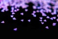 Tiny purple hearts on a black background, top view, carnival, night party invitation or festive background, valentine`s day