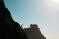 Tiny silhouette of a man on a rugged cliff in Aftas Beach. Rock formation in the chill coastal town of Mirleft, Morocco. Royalty Free Stock Photo