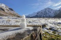 A tiny snowman against the snow-capped mountains on a sunny day. Beautiful autumn valley in the background Royalty Free Stock Photo