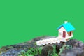 Tiny Toy House Set on a Tree Stump against Clean Green Backdrop