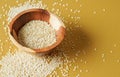 Tiny white sesame seeds in small wooden bowl, on yellow board, closeup photo Royalty Free Stock Photo