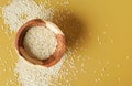 Tiny white sesame seeds in small wooden bowl, on yellow desk, view from above Royalty Free Stock Photo