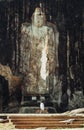 Tiny woman figurine stands at the foot of oldest Buddha idol in