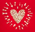 Tiny wooden arrows pointing to a large red heart on red background