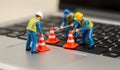 Tiny workers busy fixing a computer with traffic cones on a laptop keyboard Royalty Free Stock Photo