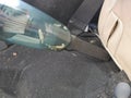 The tip / head of a portable handheld vacuum cleaner being used to clean up narrow area inside a car