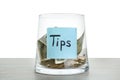 Tip jar with money on wooden table against white background Royalty Free Stock Photo