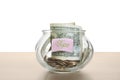 Tip jar with money on wooden table against white background Royalty Free Stock Photo