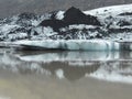 Tip of SÃÂ³lheimajÃÂ¶kull glacier in iceland, with dark layers of soil, reflected in water