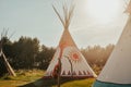 Tipi house in the forest against the background of trees, camping, village in the forest, camping. Indian teepee house at sunset