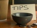 Tipping bowl in coffee shop with coins and coffee cup Royalty Free Stock Photo