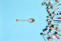 Tips of cutlery. Top view photo one table spoon surrounded of variety of antique silverware and gold spoons against blue