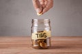 Tips. Glass jar with coins and an inscription tips. Man holds coin in his hand Royalty Free Stock Photo