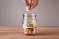 Tips. Glass jar with coins and an inscription tips. Man holds coin in his hand Royalty Free Stock Photo