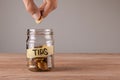 Tips. Glass jar with coins and an inscription tips. Man holds coin Royalty Free Stock Photo