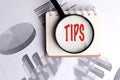 Tips text highlighted by magnifying glass on notepad with business graphs in the background Royalty Free Stock Photo