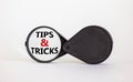 Tips and tricks symbol. Magnifying glass with words `Tips and tricks`. Beautiful white background. Business, tips and tricks Royalty Free Stock Photo