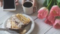 Tiramisu cake, female hands holding smartphone and cup of coffee and pink tulips Royalty Free Stock Photo