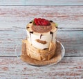 Tiramisu in a glass with berries, mint and coffee beans on a light wooden background