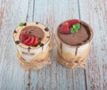 Tiramisu in a glass with berries, mint and coffee beans on a light wooden background