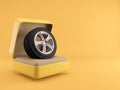 Tire and alloy rim in ring box with yellow background. Royalty Free Stock Photo