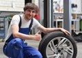 Tire change in a car workshop by mechanic - portrait og smiling