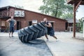 Tire flip exercise. Bald sportsman is engaged in workout with heavy tire in street gym. Concept lifting, workout training. Under Royalty Free Stock Photo