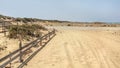 Tire and foot prints on a road leading to beach covered in sand. Sea in distant background Royalty Free Stock Photo