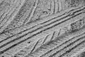 Tire imprints on sandy desert road in black and white.