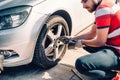 Tire maintenance, damaged car tyre or changing seasonal tires using wrench. Changing a flat car tire on the sideroad or in the cou