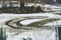 Tire marks in snow and grassy lawn in yard with boulder fence