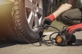 Tire pump inflating car wheel. Tyre inflator in man hands with manometer