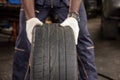 A tire at the repair garage. mechanic hands pushing a black tire in the workshop.