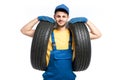 Tire service worker in blue uniform holds car tyre Royalty Free Stock Photo