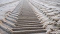 a tire track in the sand on a beach next to water Royalty Free Stock Photo