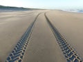 Tire tracks on smooth sandy deserted beach Royalty Free Stock Photo