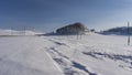 Tire tracks are visible in the endless snow-covered valley.