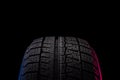 tire with a tread for driving on ice and snow on a black background with an image blue red illumination Royalty Free Stock Photo