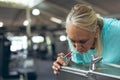 Tired active senior woman drinking tap water in fitness center