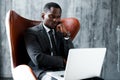Tired african american businessman working at laptop and thinking, leaning on fist Royalty Free Stock Photo