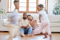 Tired African American couple sitting on the lounge floor looking tired and drained while their energetic children plays Royalty Free Stock Photo