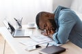 Tired african american freelancer guy sleeping at desk with laptop and papers Royalty Free Stock Photo