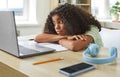 Tired African American girl teen bored with head on table in front of laptop sits at desk at home Royalty Free Stock Photo