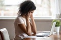 Unwell biracial woman suffer from headache working at laptop