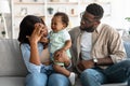 Tired African American parents sitting with crying kid on sofa Royalty Free Stock Photo