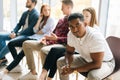 Tired African-American young man job candidates looking at camera while waiting interview with hr, sitting in queue line Royalty Free Stock Photo