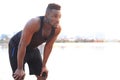 Tired African man in sports clothing looking away while standing outdoors, in beach at sunset or sunrise. Royalty Free Stock Photo